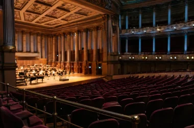 Elegant konsertsal med klassisk arkitektur och tomma sittplatser i burgundy