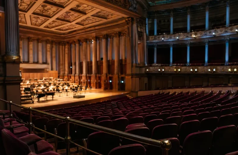 Elegant konsertsal med klassisk arkitektur och tomma sittplatser i burgundy
